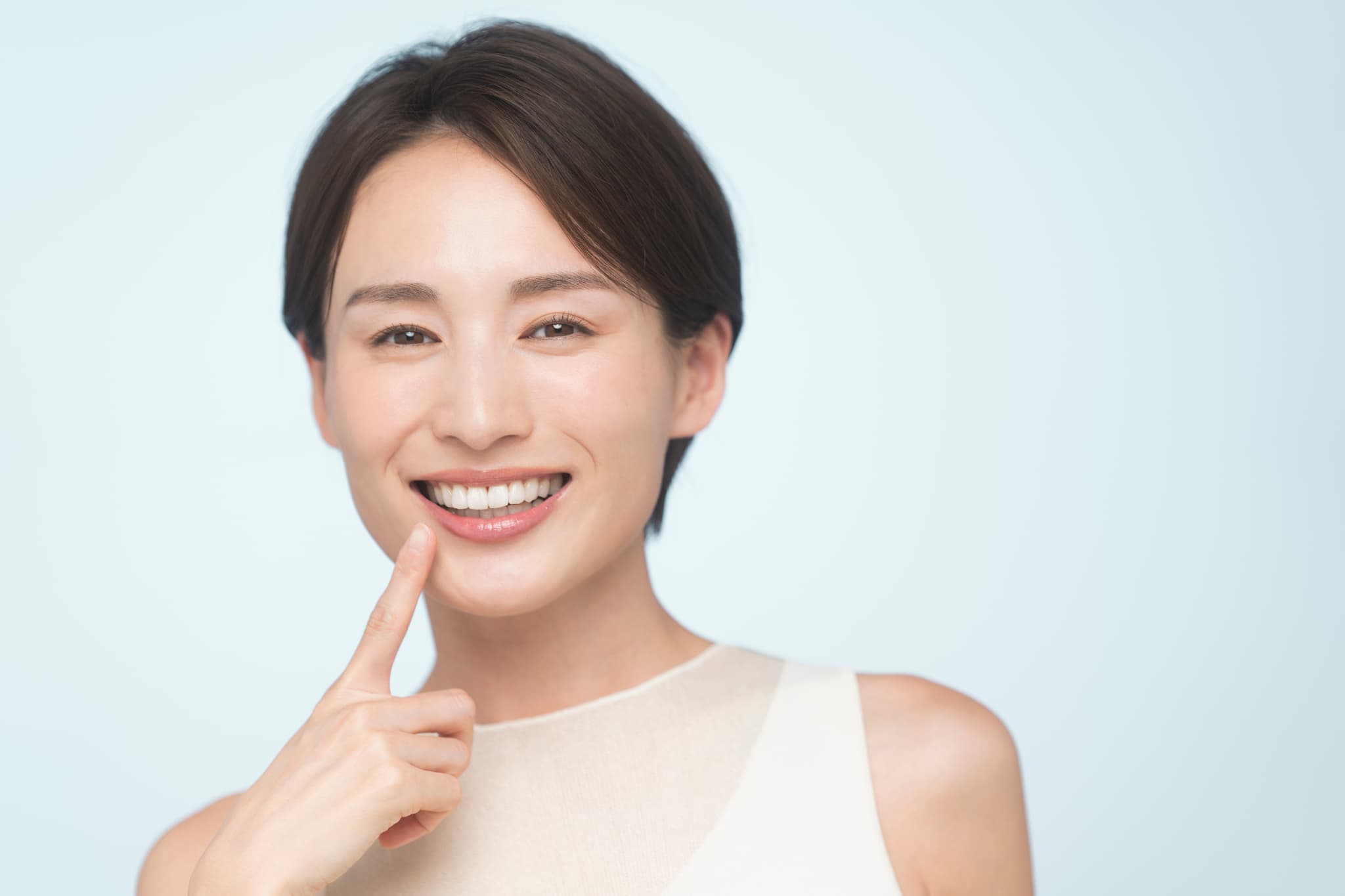 インプラントにした歯を指さして笑顔を見せる女性