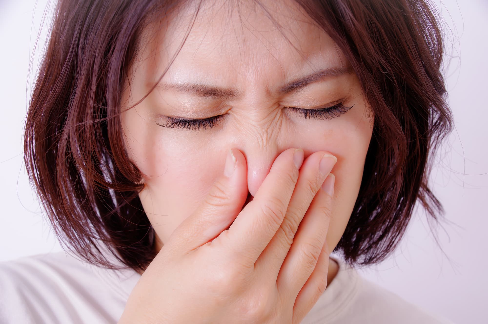 口臭が臭いと感じ鼻をつまむ女性