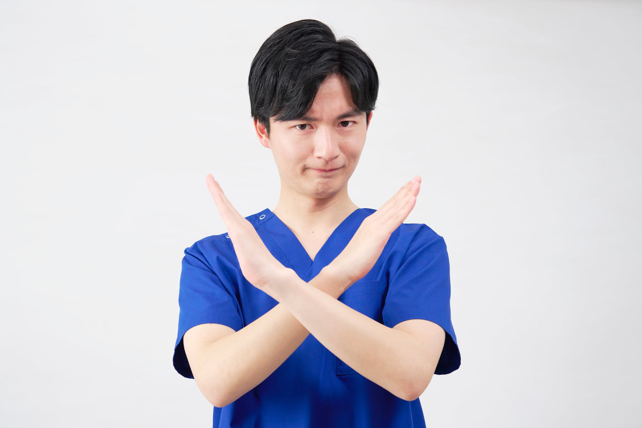 インプラント治療ができない人について説明する両手でバツマークをした歯科医