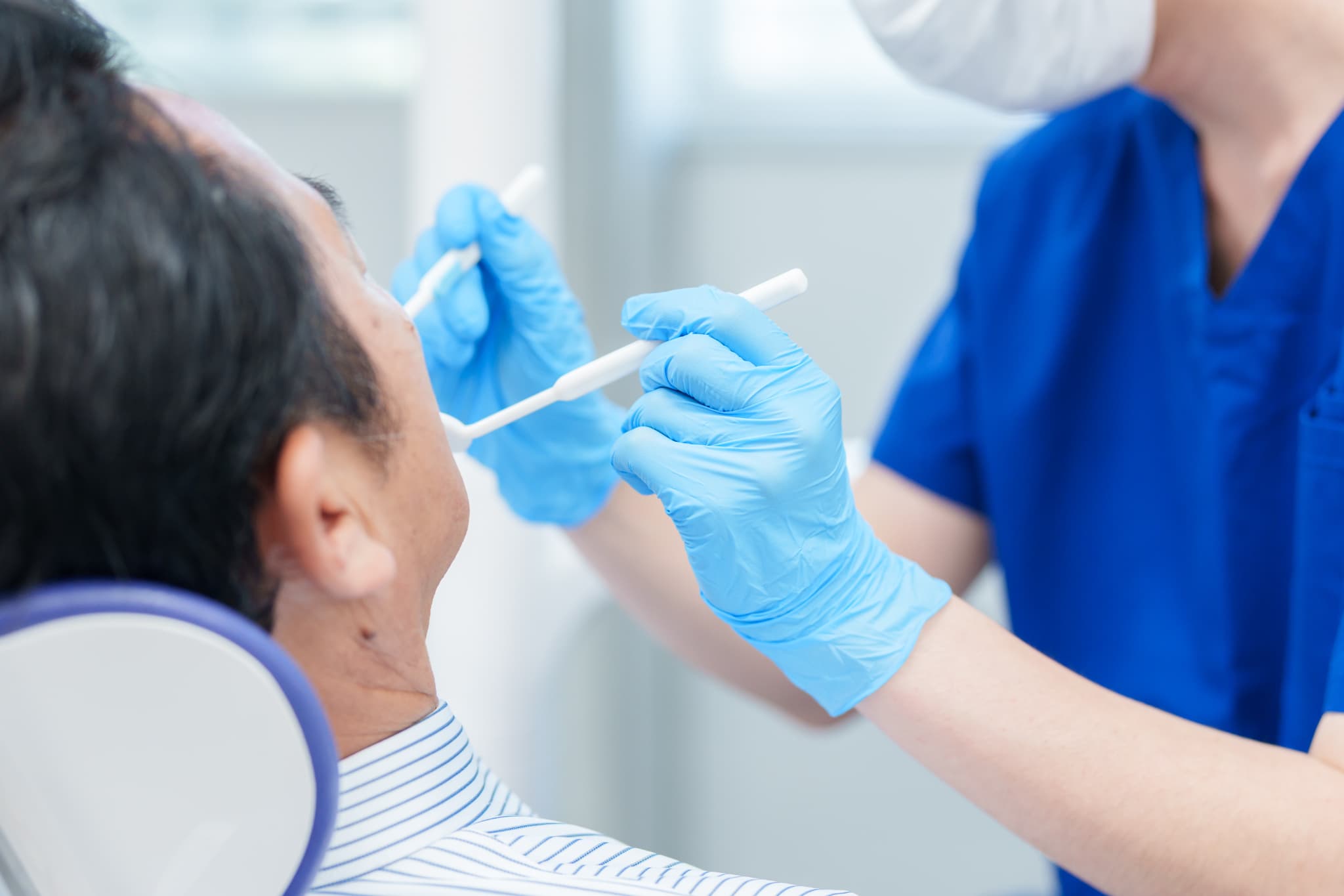 インプラント治療後に腫れが続いて歯科医の診察を受ける男性